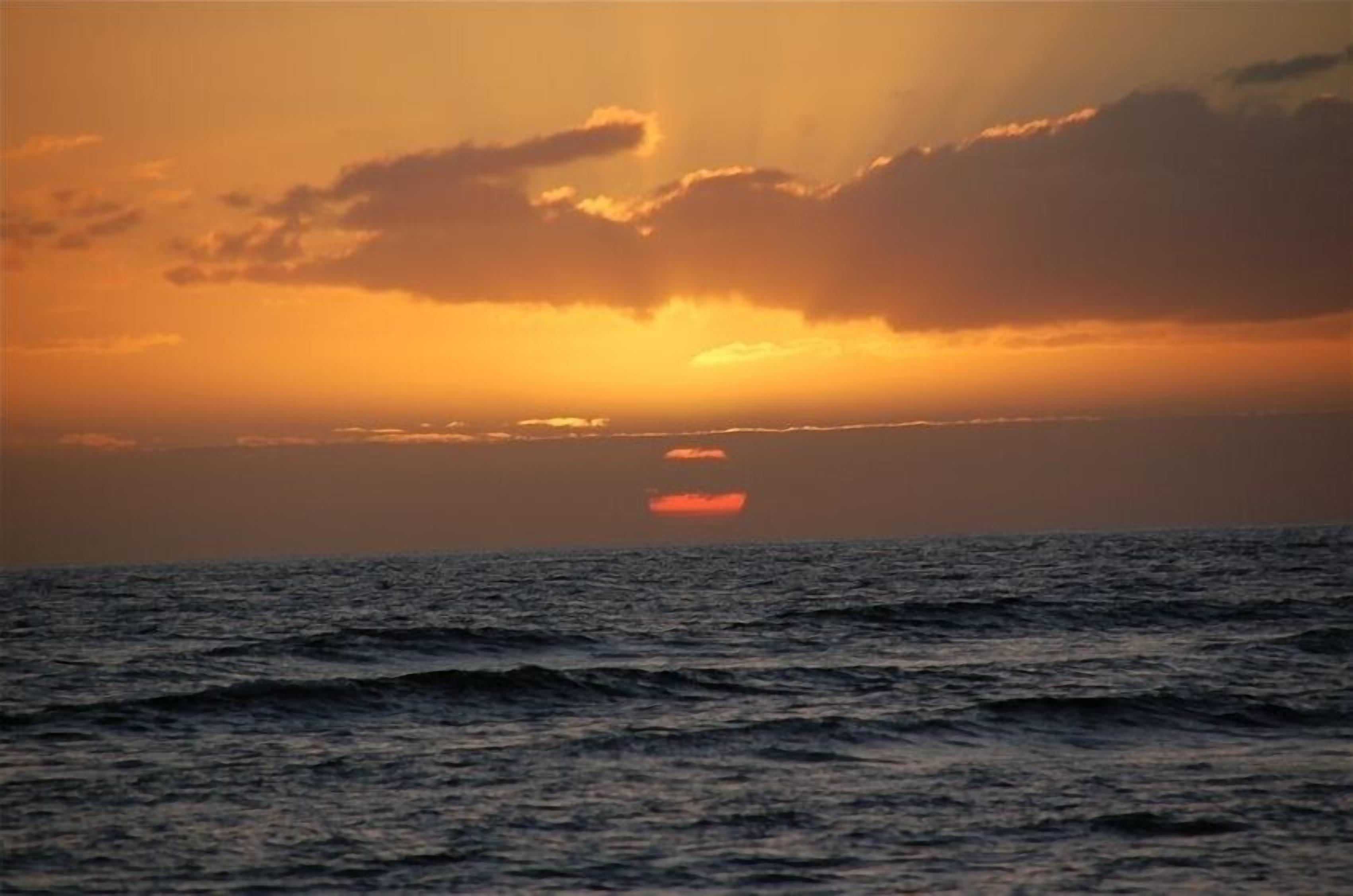 A sunset over the ocean with waves.