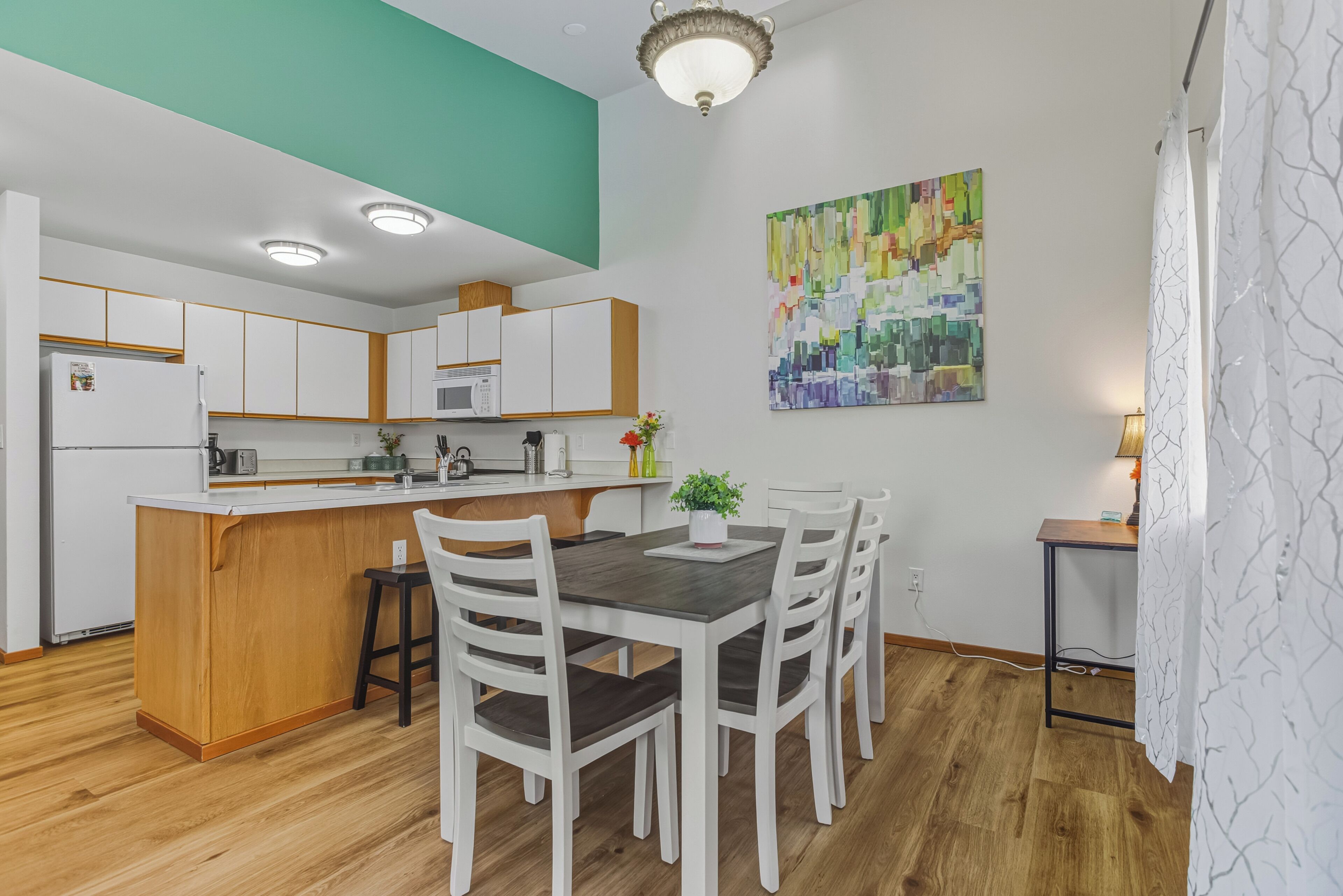 Une cuisine moderne avec des meubles blancs, un îlot central en bois et un coin repas avec des chaises blanches.