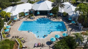 An aerial view of a resort with a central swimming pool surrounded by lounge areas and palm trees. - Windsor Palms 4 Bedroom Vacation Home 2252 (Kissimmee)