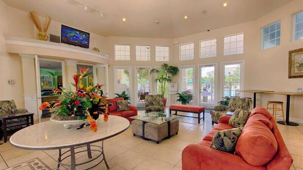 A spacious living room with a round table, red sofas, and a large window providing natural light. - Windsor Palms 4 Bedroom Vacation Home 2252 (Kissimmee)