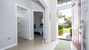 A hallway with a red door leading to a balcony, a white door to a bedroom, and a white wall with a light switch. - Windsor Palms 4 Bedroom Vacation Home 2252 (Kissimmee)