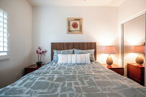 Une chambre à coucher avec un lit, une table de chevet, une lampe et un tableau accroché au mur.