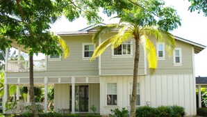 A two-story house with a front porch, a covered patio, and a well-maintained lawn.