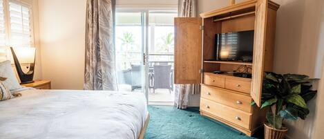 A hotel room with a bed, a TV on a wooden stand, a plant, and a view through the door.