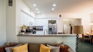 Una cocina moderna con armarios blancos, un refrigerador de acero inoxidable y una encimera con una planta en maceta.
