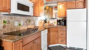 A kitchen with wooden cabinets, a white microwave, a stove, and a refrigerator.