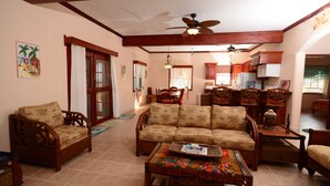 A living room with a sofa, chairs, a coffee table, and a ceiling fan. - Rustic Ocean front Home with POOL-115' of beachfront 250 ft Dock-
GOLD STANDARD (San Pedro)