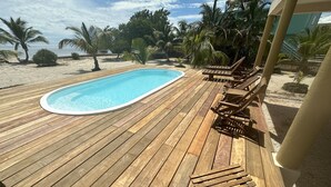 A wooden deck with a pool, lounge chairs, and palm trees. - Rustic Ocean front Home with POOL-115' of beachfront 250 ft Dock-
GOLD STANDARD (San Pedro)
