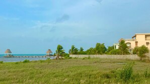 A coastal hotel with a pier, thatched-roof structures, and lush greenery. - Rustic Ocean front Home with POOL-115' of beachfront 250 ft Dock-
GOLD STANDARD (San Pedro)