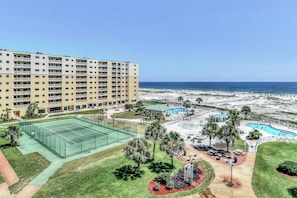Un hotel con campo da tennis, area piscina e vista sulla spiaggia.