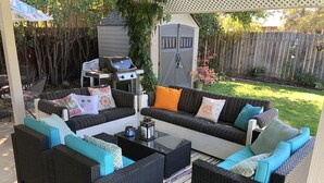 Ein Patio mit einer Eckcouch, zwei Sesseln und einem Couchtisch.