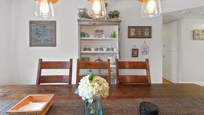 Ein Essbereich mit Holztisch, drei Stühlen, einer Blumenvase und einer Pendelleuchte.