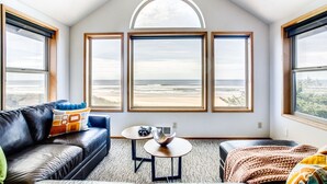 Une chambre avec vue sur la plage, un canapé en cuir, une petite table ronde et une fenêtre donnant sur l’océan.