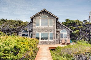 A two-story house with a wooden exterior, large windows, and a wooden deck.