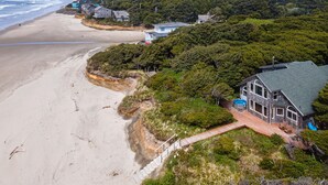 Une propriété située sur la côte, dotée d’une grande maison, d’une piscine et offrant une vue sur la plage.