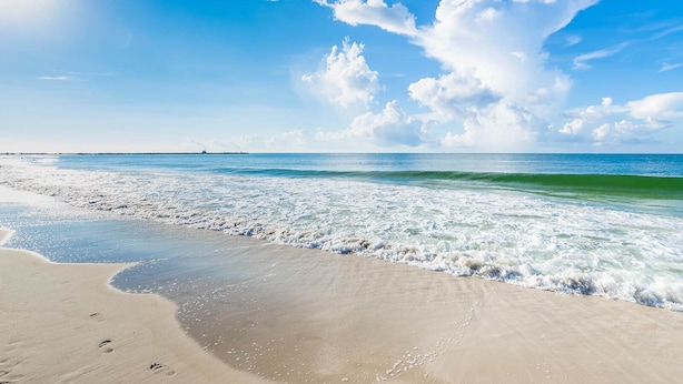 Una playa con cielo despejado y olas.