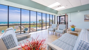 Una habitación amplia con ventanas grandes, vista a la piscina y un área de descanso con una planta.