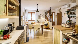 A cozy kitchen with a dining area, wooden cabinets, and a central island. - Villa PoliFlora is a modern apartment in Monticchiello of Pienza in Tuscany. (Monticchiello)