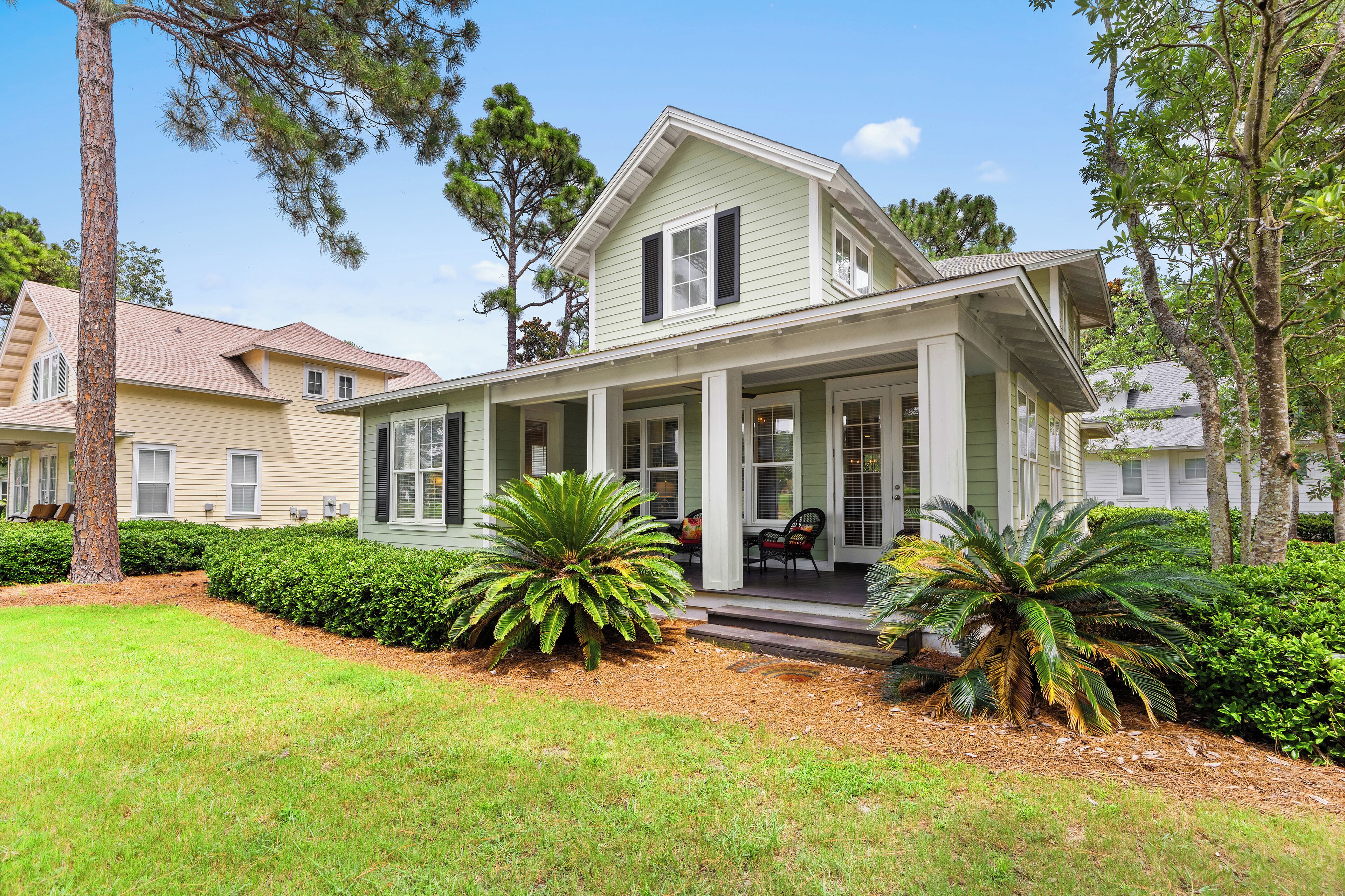A two-story house with a porch, surrounded by well-maintained landscaping and trees.