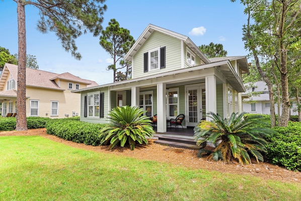 A two-story house with a porch, surrounded by well-maintained landscaping and trees.