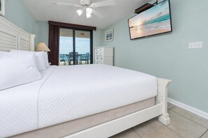 Une chambre avec un lit, un ventilateur de plafond, une télévision et une vue sur l’océan.