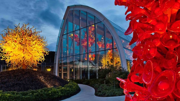 Ein modernes Gebäude mit einer geschwungenen Glasfassade und einem Skulpturengarten mit abstrakter Glasinstallation.
