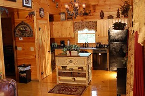 A rustic kitchen with wooden cabinets, a central island, and a refrigerator.