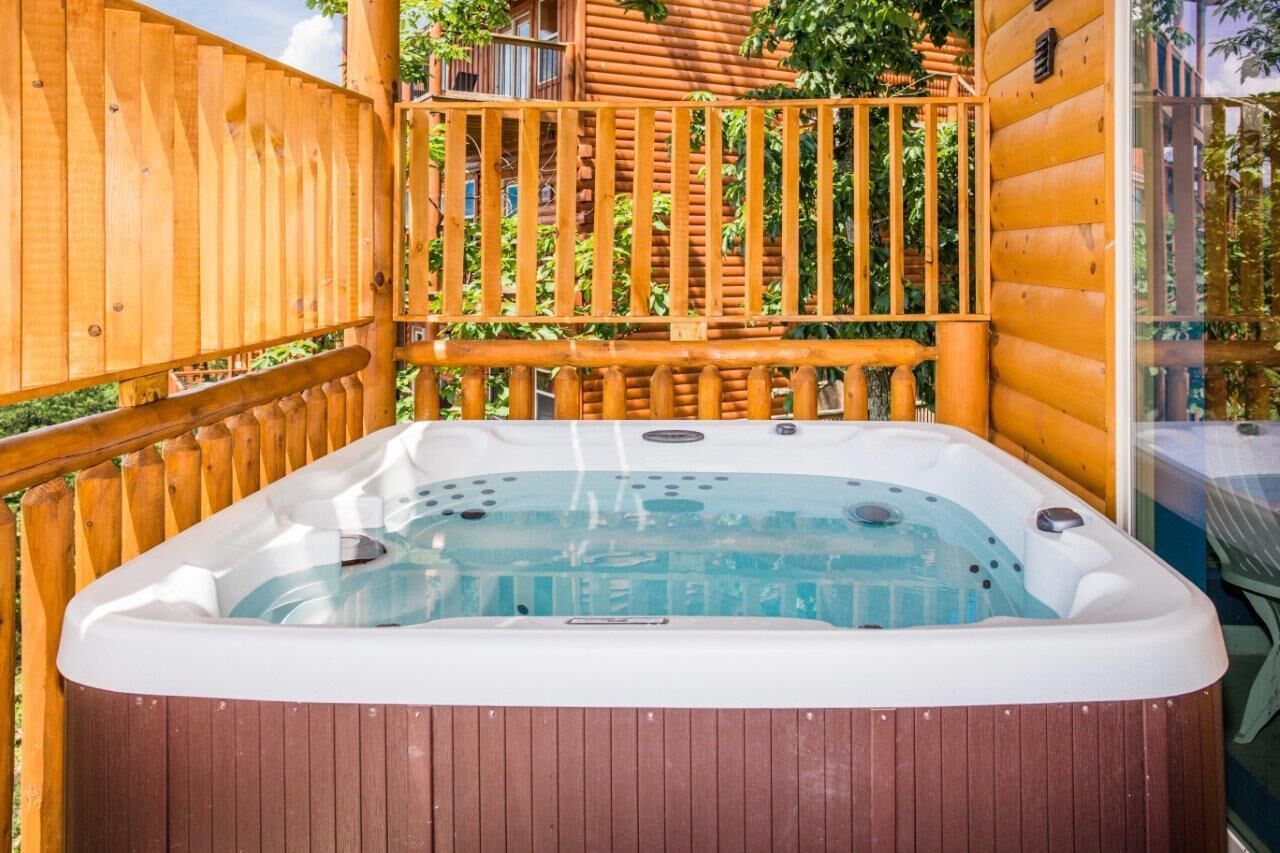 Un bain à remous dans un chalet en bois, avec une terrasse en bois et une clôture en bois.