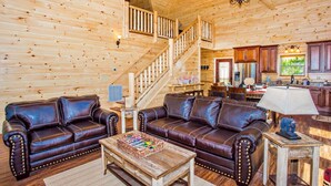 Un interior de madera con una escalera, sofás de cuero, una mesa de centro y armarios de madera.