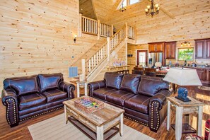 A wooden interior with a staircase, leather sofas, a coffee table, and wooden cabinets. - 5 Miles to Gatlinburg! Indoor Heated Pool/ Theater Room/ Hot tub/ Amazing Views! (Pigeon Forge)