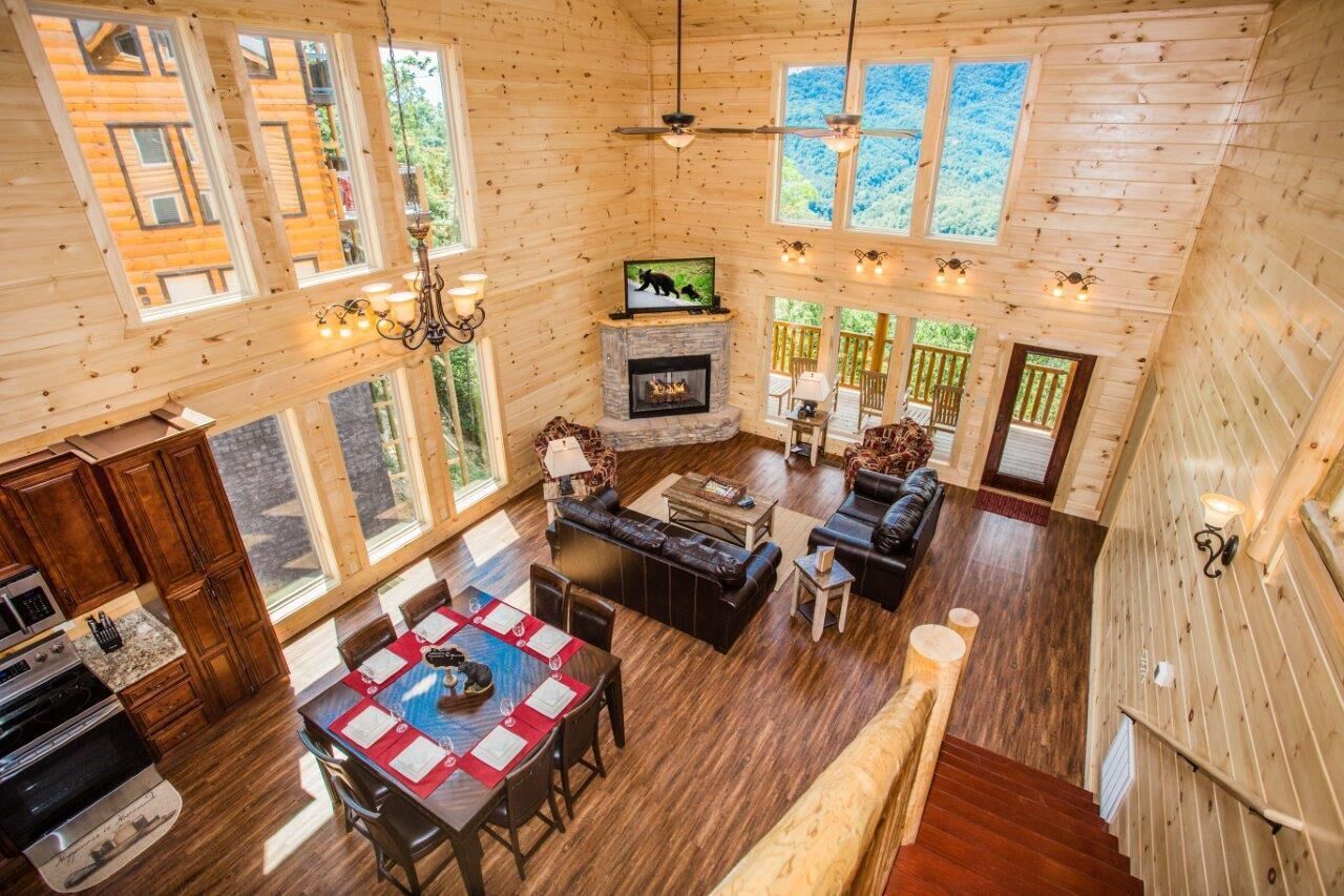 Interior espacioso de una cabaña de troncos con chimenea, comedor y una sala de estar acogedora.