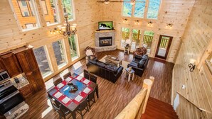 Interior espacioso de una cabaña de troncos con chimenea, comedor y una sala de estar acogedora.