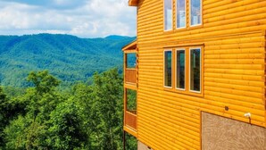 Una cabaña de madera con balcón, rodeada de montañas verdes y exuberantes.