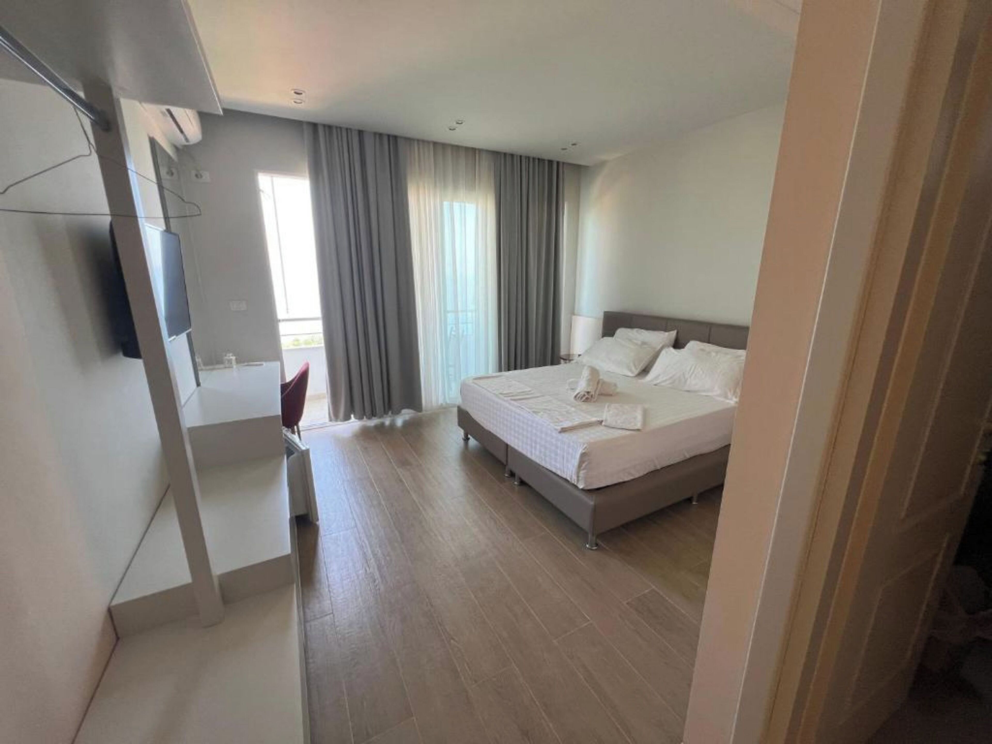 A hotel room with a bed, a desk, a chair, and a TV.