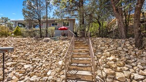 A stone staircase leading to a house surrounded by trees and a rocky landscape. - REMODELED 3Bd/2Bth TreeTop House -> Downtown Location w/ Views & 5-STAR REVIEWS! (Prescott)