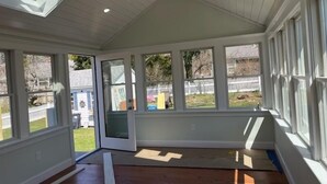 Una habitación luminosa con ventanas amplias, tragaluces y suelo de madera.