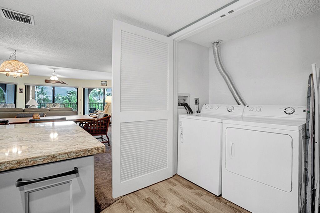 A compact kitchen with a built-in oven, a washing machine, and a large window offering a view of the outdoors.