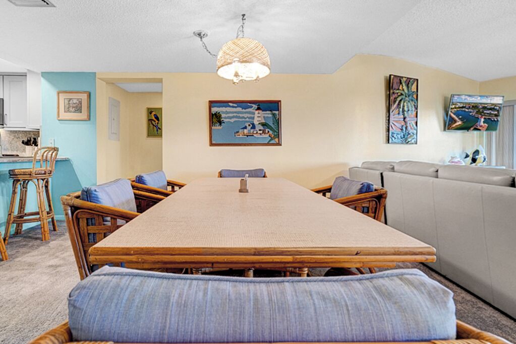A dining area with a long wooden table, wicker chairs, and a cushioned bench.