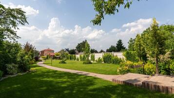 A well-maintained garden with a paved walkway, neatly trimmed grass, and various plants and shrubs.