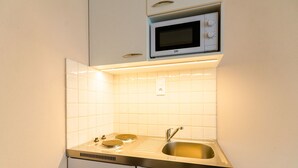 Une cuisine compacte équipée d’un four à micro-ondes, de deux plaques de cuisson et d’un évier.