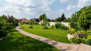 A well-maintained garden with a curved pathway, neatly trimmed grass, and various plants.