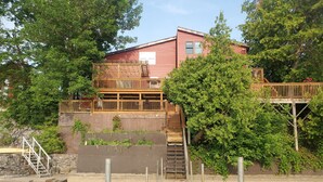 Een huis met een houten terras en een steiger die in het water uitloopt.