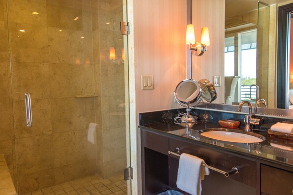 Un baño moderno con cabina de ducha de vidrio, tocador con lavabo y un espejo grande.