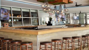 A modern bar area with a long counter, multiple stools, and a variety of bar tools and bottles.
