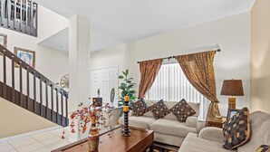 Sala de estar com sofá, mesa de centro e escada.