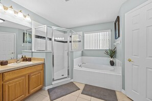A modern bathroom with a glass-enclosed shower, a freestanding bathtub, and a vanity with a sink and storage.