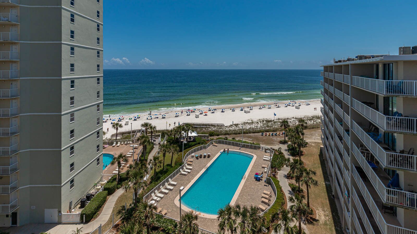 A hotel with a pool, beach, and ocean view.
