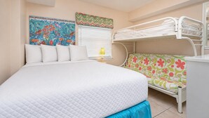 A room with a bed, bunk beds, a colorful wall mural, and a window with blinds.
