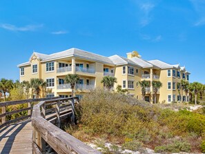 A multi-story hotel with balconies, a wooden boardwalk, and surrounding vegetation. - 105E 2Bed/2Bath Beautiful Gulf View (Gulf Shores)