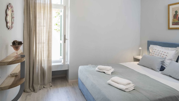 A bedroom with a bed, bedside table, and a window with curtains. - Athenian House in Plaka (Athens)